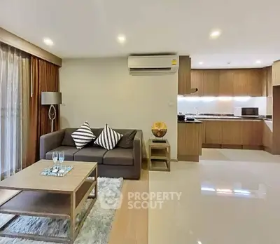 Modern open-layout living room with sleek kitchen, cozy sofa, and stylish decor in a contemporary apartment.