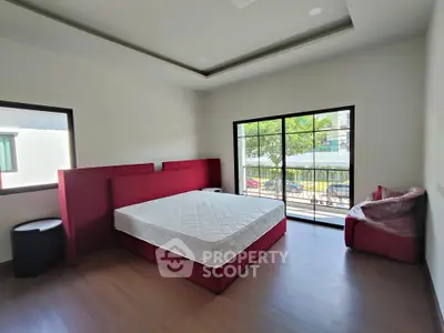 Spacious bedroom with large window and modern red furniture