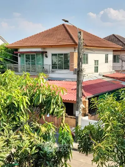 Charming suburban house with tiled roof and lush greenery, perfect for family living.