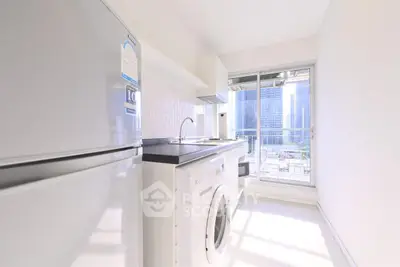 Bright modern kitchen with washing machine and city view from window.
