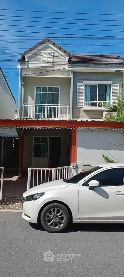Charming two-story house with balcony and driveway in a suburban neighborhood.