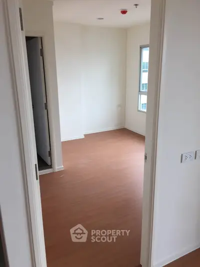 Spacious empty room with wooden flooring and natural light