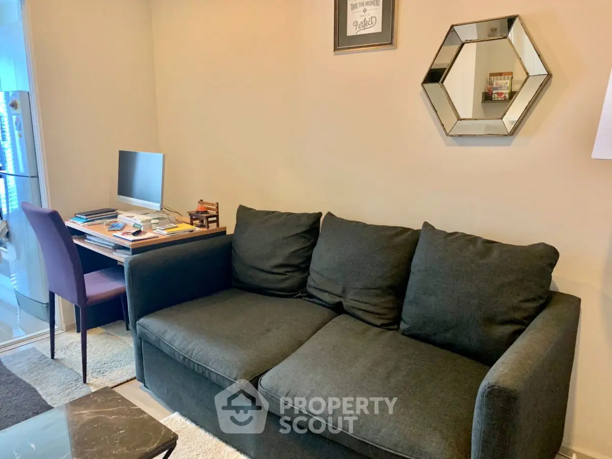 Cozy living room with modern sofa and study area, perfect for work-from-home setup.