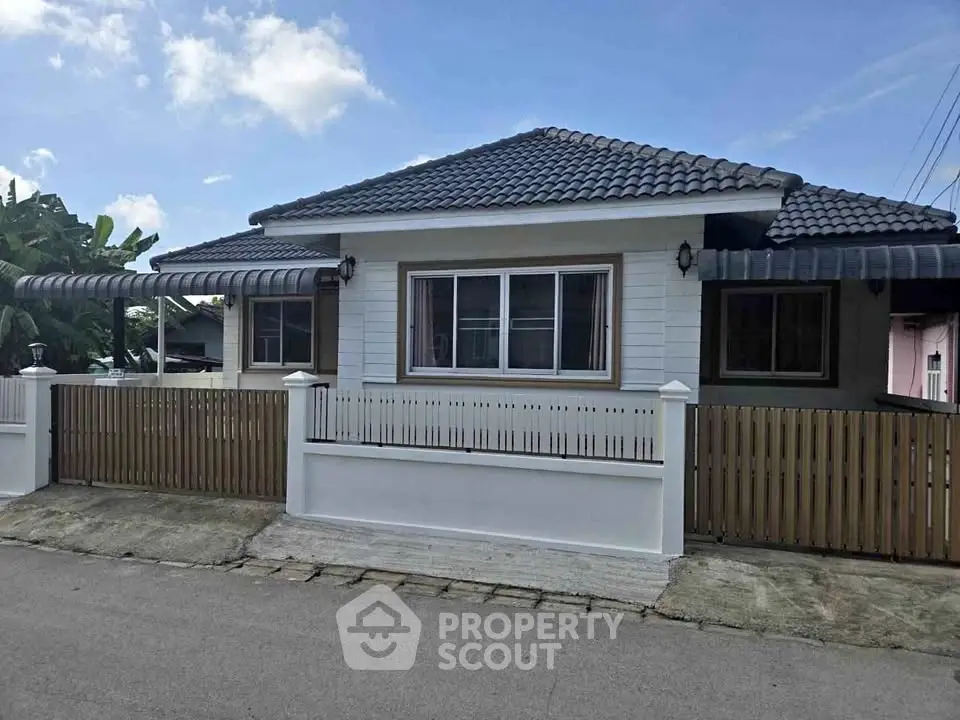 Charming single-story house with tiled roof and fenced yard in a serene neighborhood.
