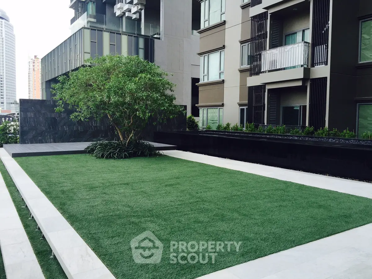 Modern urban building with lush green garden and sleek architectural design.