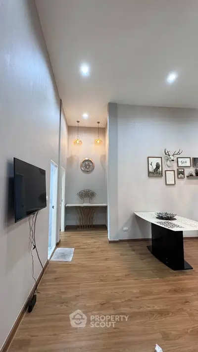 Spacious living room with modern decor and wall-mounted TV, featuring elegant lighting and wooden flooring.