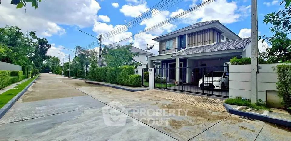 Charming suburban house with gated entrance and lush greenery on a sunny day.