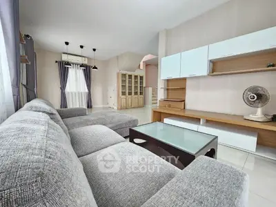 Spacious living room with modern grey sofa, sleek white storage units, and ample natural light, perfect for family relaxation and entertaining guests.