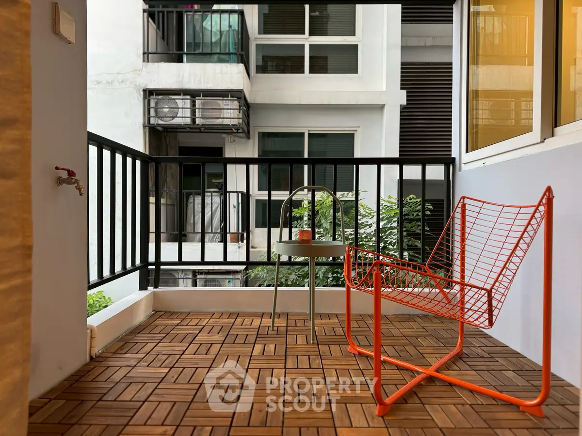 Chic urban balcony with modern chair and wooden deck tiles, perfect for relaxation.