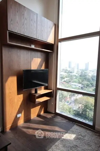 Modern living room with large window and wall-mounted TV, offering a stunning city view.