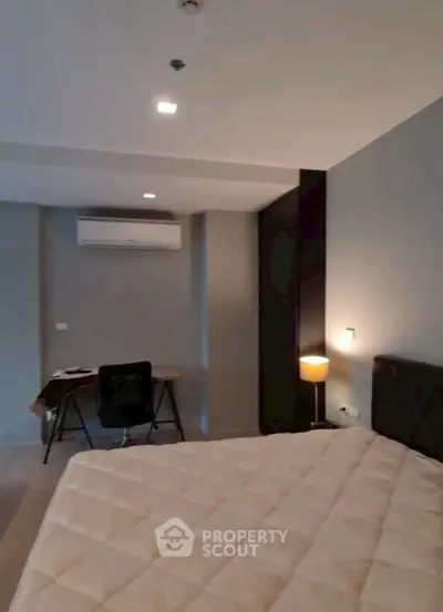 Modern bedroom with cozy lighting and workspace, featuring air conditioning.