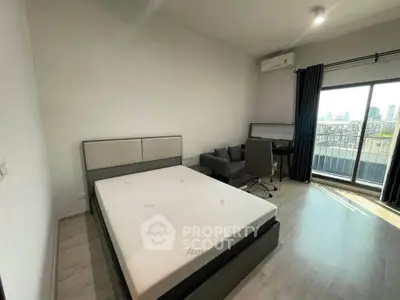Modern bedroom with city view, featuring a cozy bed, desk, and balcony access.