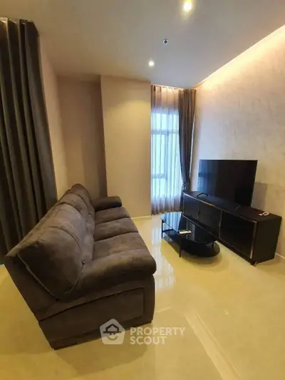 Modern living room with plush sofa and sleek TV setup in a cozy apartment.