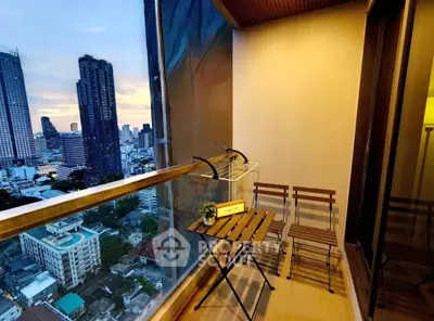 Stunning city view from a modern high-rise balcony with cozy seating area.