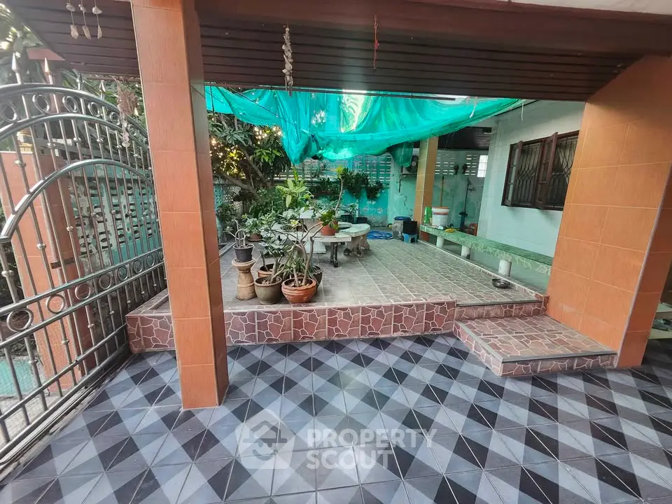 Charming outdoor patio with tiled flooring and lush greenery, perfect for relaxation and entertaining.