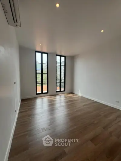 Spacious and well-lit living room with high ceilings, elegant hardwood floors, and modern tall windows offering plenty of natural light.