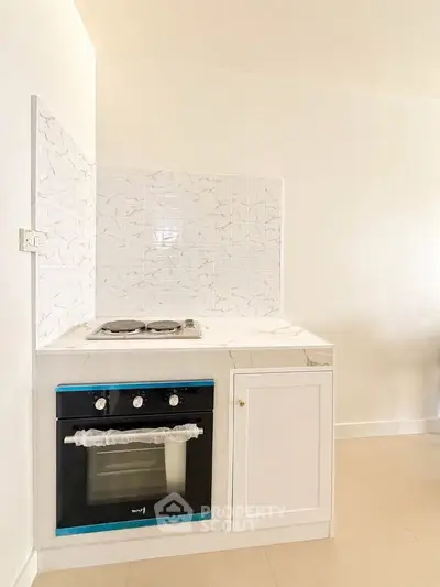 Modern kitchen with sleek white cabinetry and built-in oven, perfect for culinary enthusiasts.