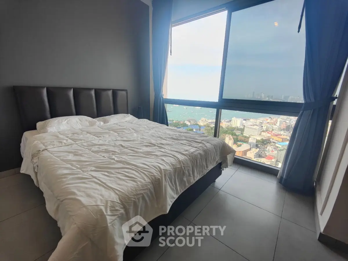 Luxurious bedroom with stunning city and sea view from large window.