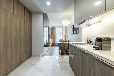 Modern kitchen with sleek cabinetry and open layout leading to elegant dining area.
