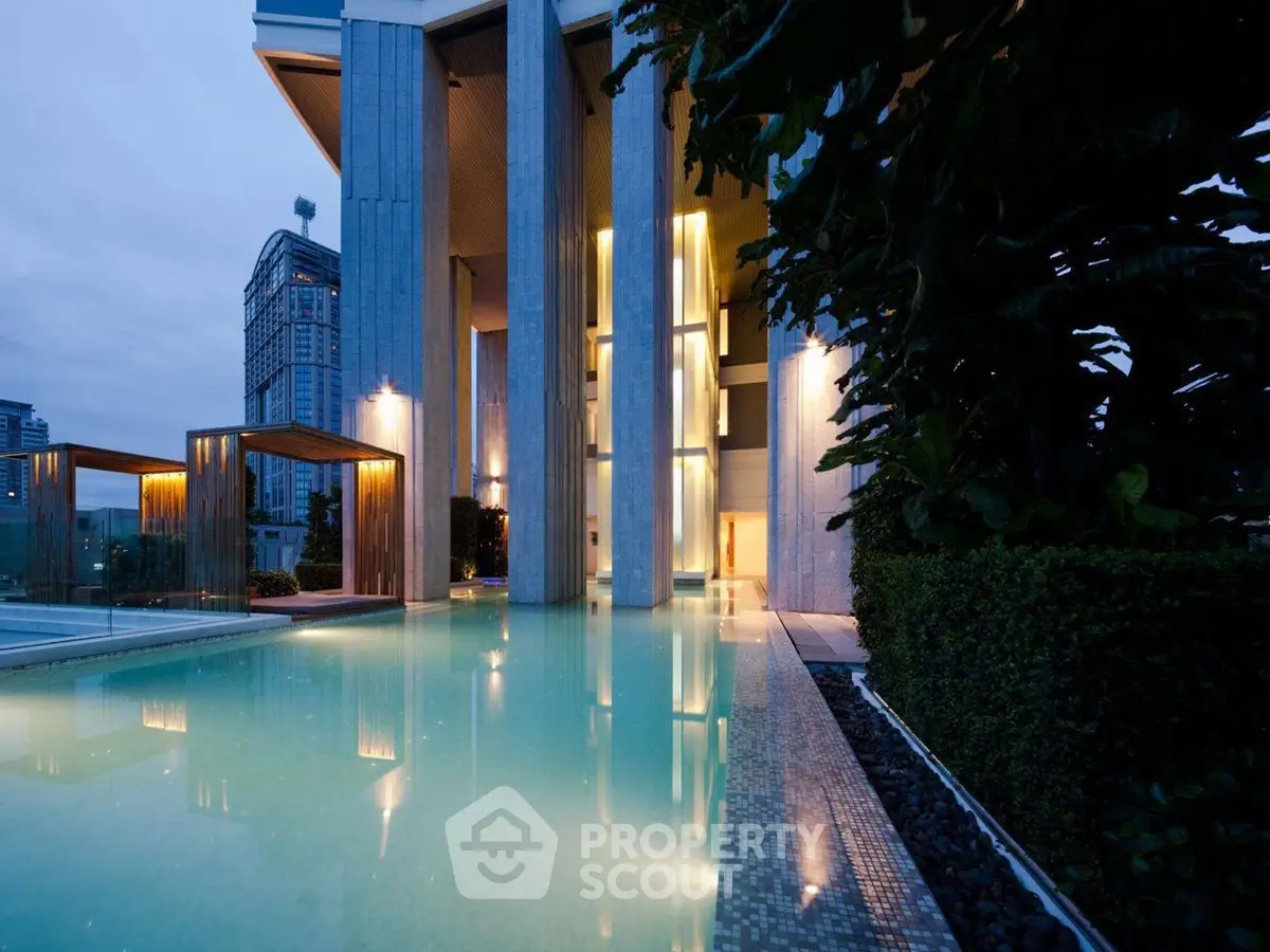 Luxurious modern building with illuminated pool and elegant architecture at dusk.