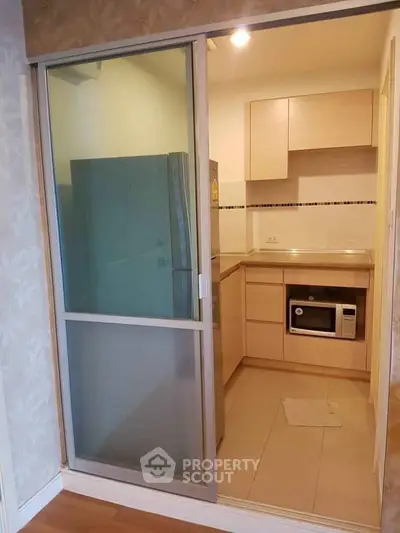 Compact kitchen with modern appliances and sliding glass door in cozy apartment.