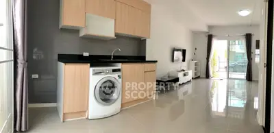 Modern living room with sleek kitchen and washing machine, open layout design.