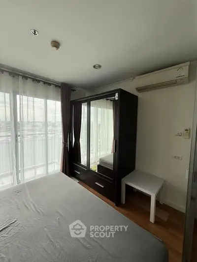 Cozy bedroom with large window and modern wardrobe in a bright apartment.