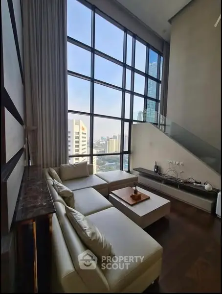 Luxurious high-rise living room with floor-to-ceiling windows and stunning city view.