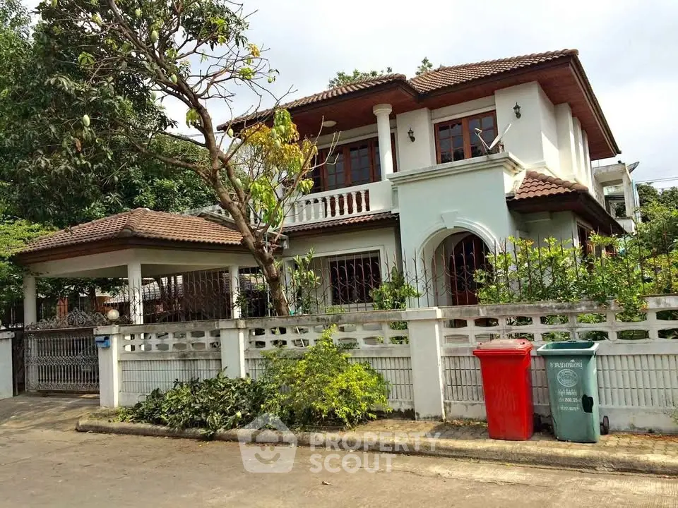 Charming two-story house with tiled roof and lush garden in a serene neighborhood.
