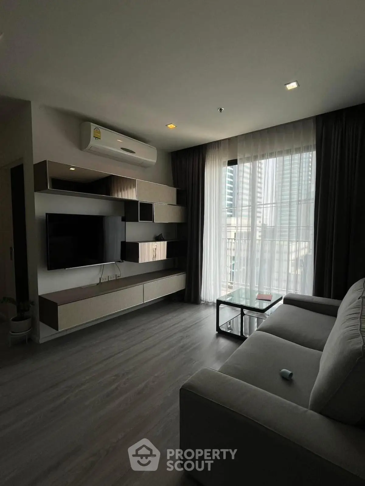 Modern living room with sleek furniture and large window offering city view