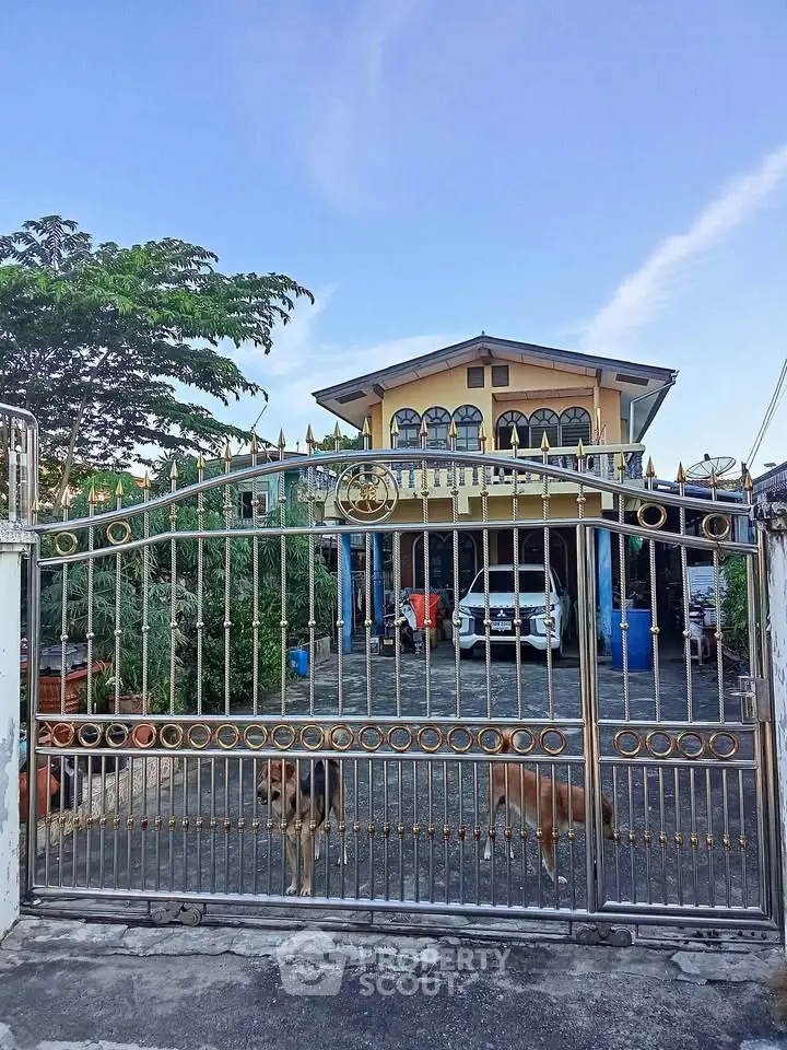 Charming two-story house with gated entrance and spacious driveway, perfect for family living.