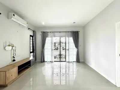 Spacious living room with large windows and modern air conditioning unit, perfect for natural light and comfort.