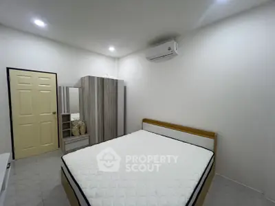 Modern bedroom with minimalist design, featuring a comfortable bed, wardrobe, and air conditioning.