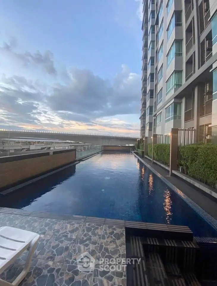 Luxurious high-rise building with stunning pool and sunset view, perfect for urban living.