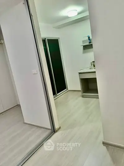 Modern minimalist interior with sleek flooring and sliding glass doors in a compact living space.