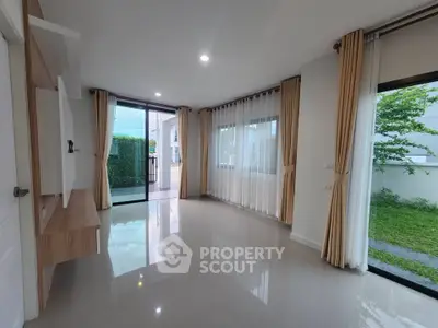 Spacious living room with large windows and modern curtains, offering a bright and airy atmosphere.