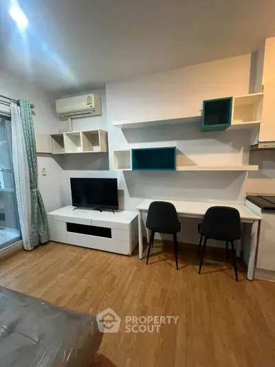 Modern living room with stylish shelving, TV, and workspace in a cozy apartment.
