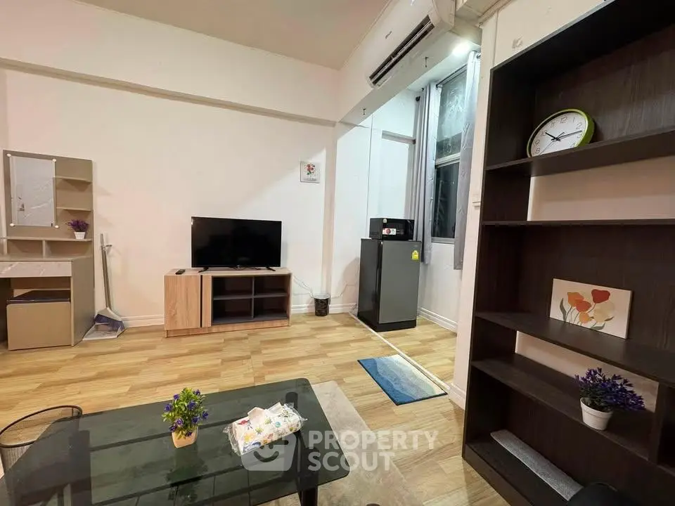 Modern living room with stylish furniture and wooden flooring, featuring a TV and air conditioning.