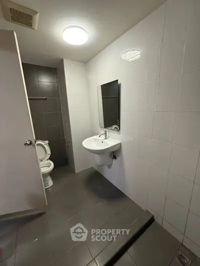 Modern bathroom with sleek fixtures and tiled walls, featuring a wall-mounted sink and toilet.