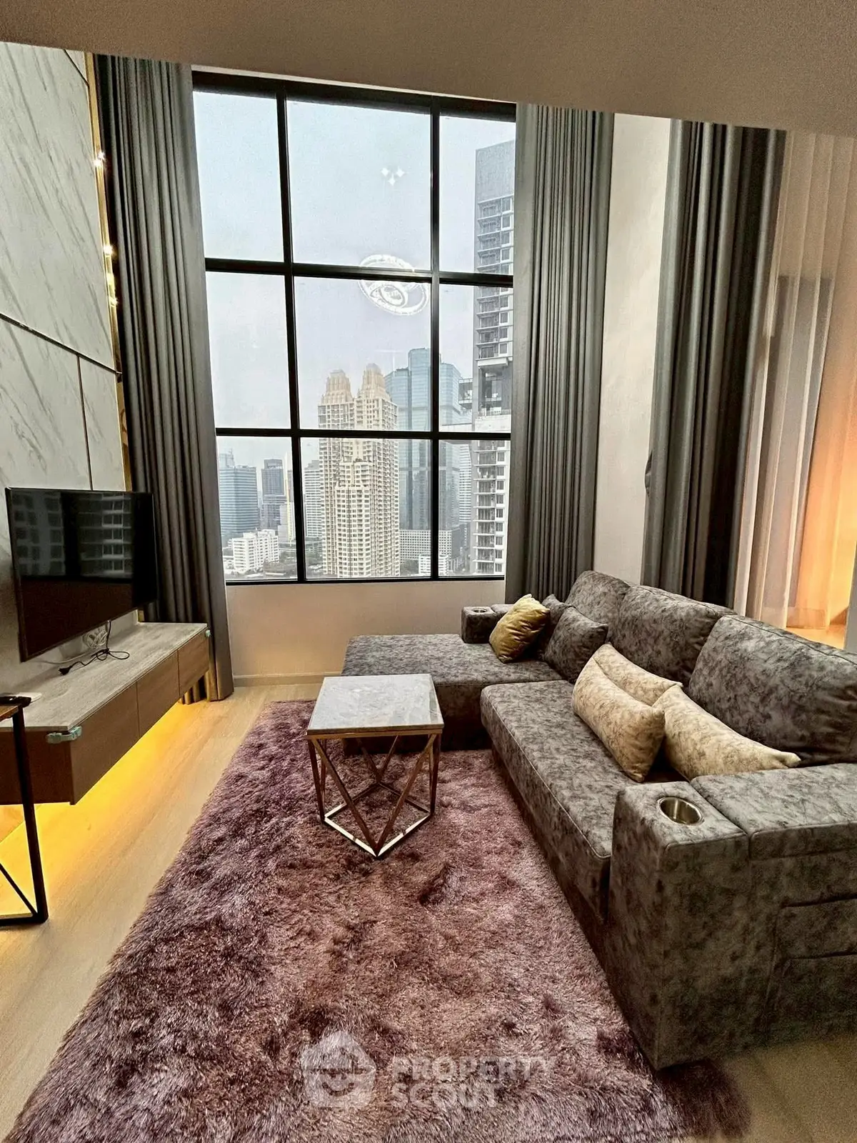 Luxurious living room with stunning city view, plush sofa, and modern decor in high-rise apartment.