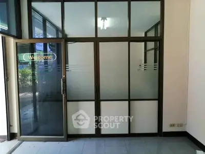 Modern office entrance with glass doors and windows, welcoming ambiance.