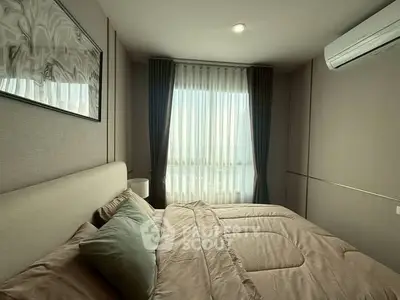 Cozy bedroom with modern decor and large window offering natural light.