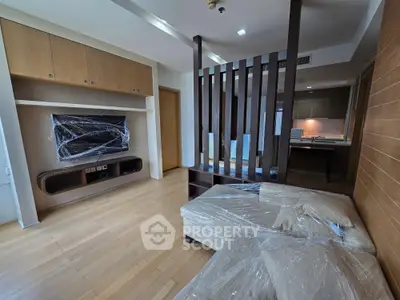 Modern living room with sleek wooden flooring and stylish partition, featuring a wrapped sofa and wall-mounted TV.