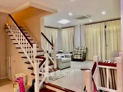 Spacious living room with elegant staircase and cozy seating area, perfect for family gatherings.
