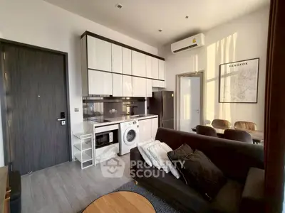 Modern living room with kitchen, washing machine, and stylish decor in Bangkok apartment.