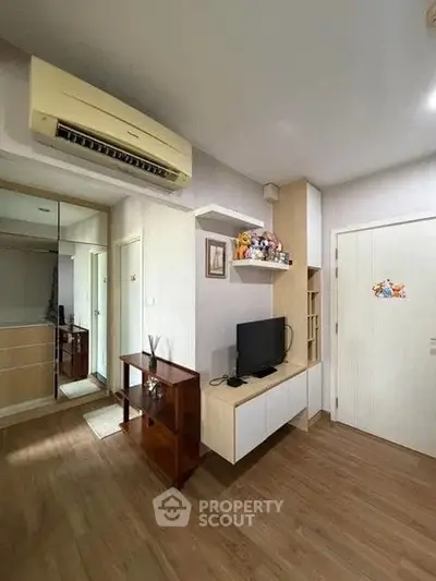 Modern living room with wooden flooring, built-in TV unit, and mirrored wardrobe.