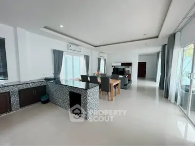 Spacious open-plan living and dining area with modern kitchen and large windows.