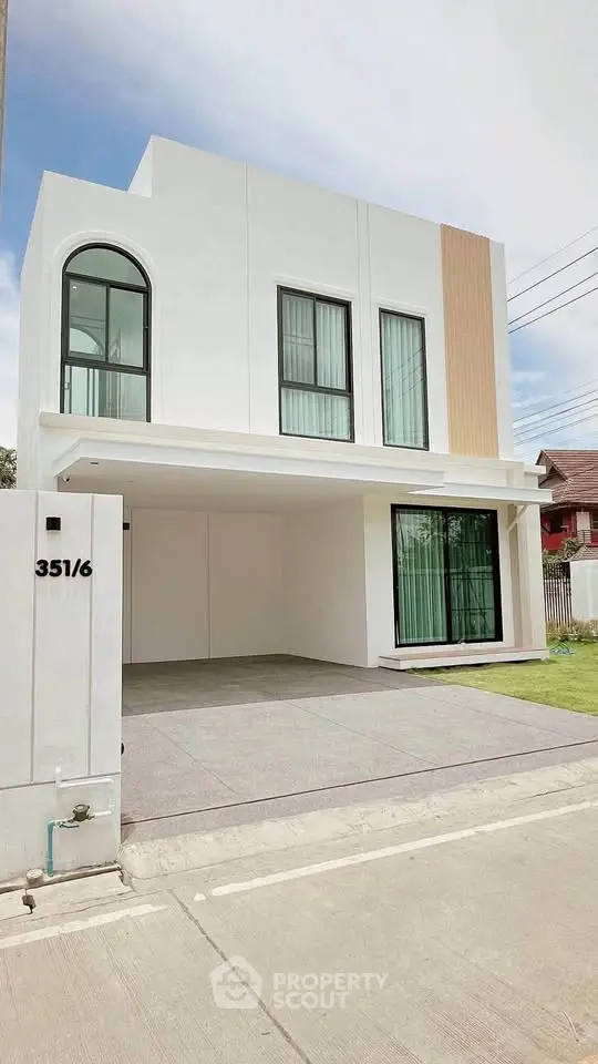 Modern two-story house with sleek design and large windows, featuring a spacious driveway and minimalistic facade.