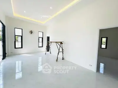 Spacious modern living room with large windows and sleek white flooring.