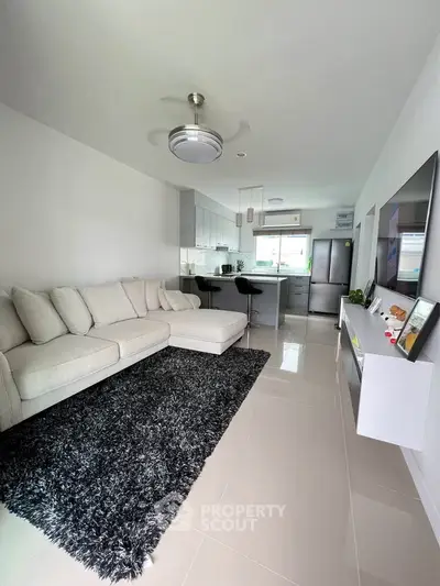 Modern open-plan living room with sleek kitchen and cozy seating area.